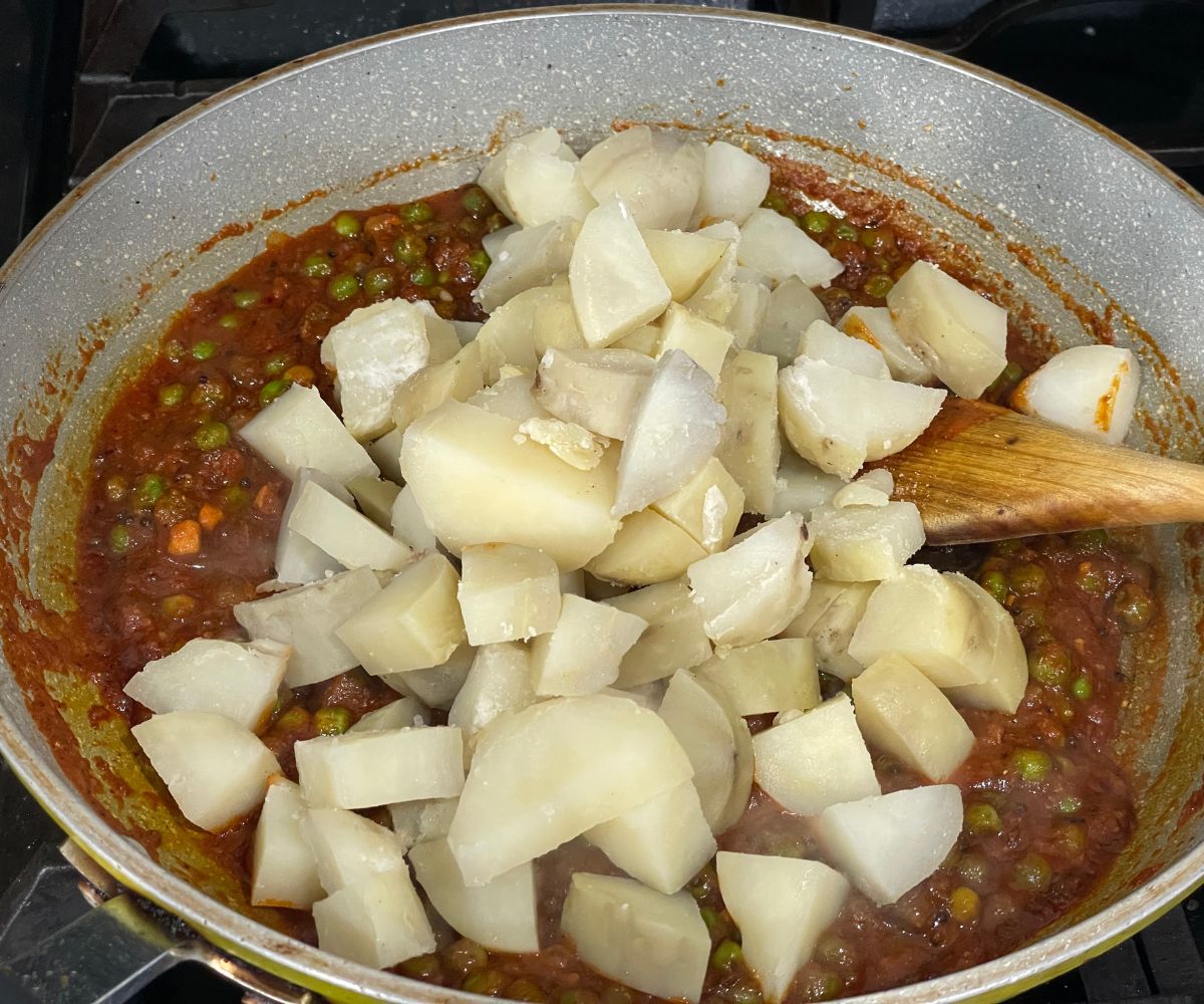 A pan has potatoes and peas with spices.