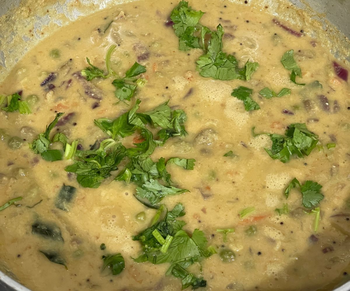 A pot of Avarekalu sagu is topped with cilantro.