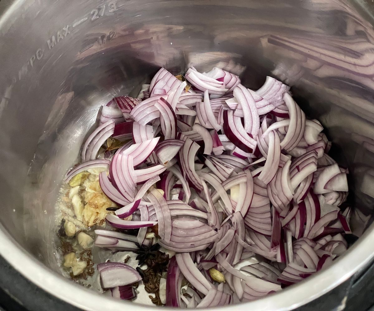 A pot is with garlic and onions along with spices.