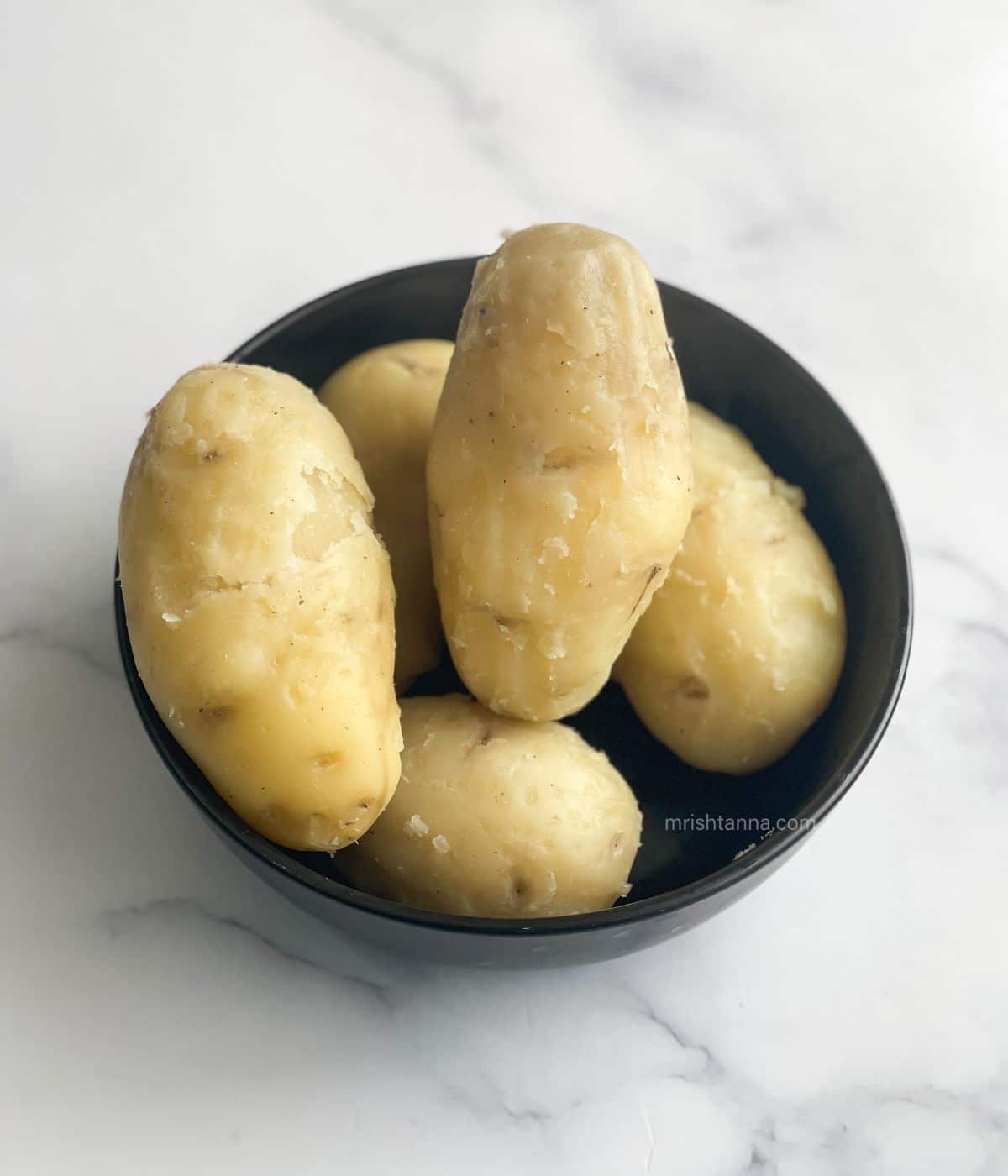 A bowl is with boiled peeled potatoes.