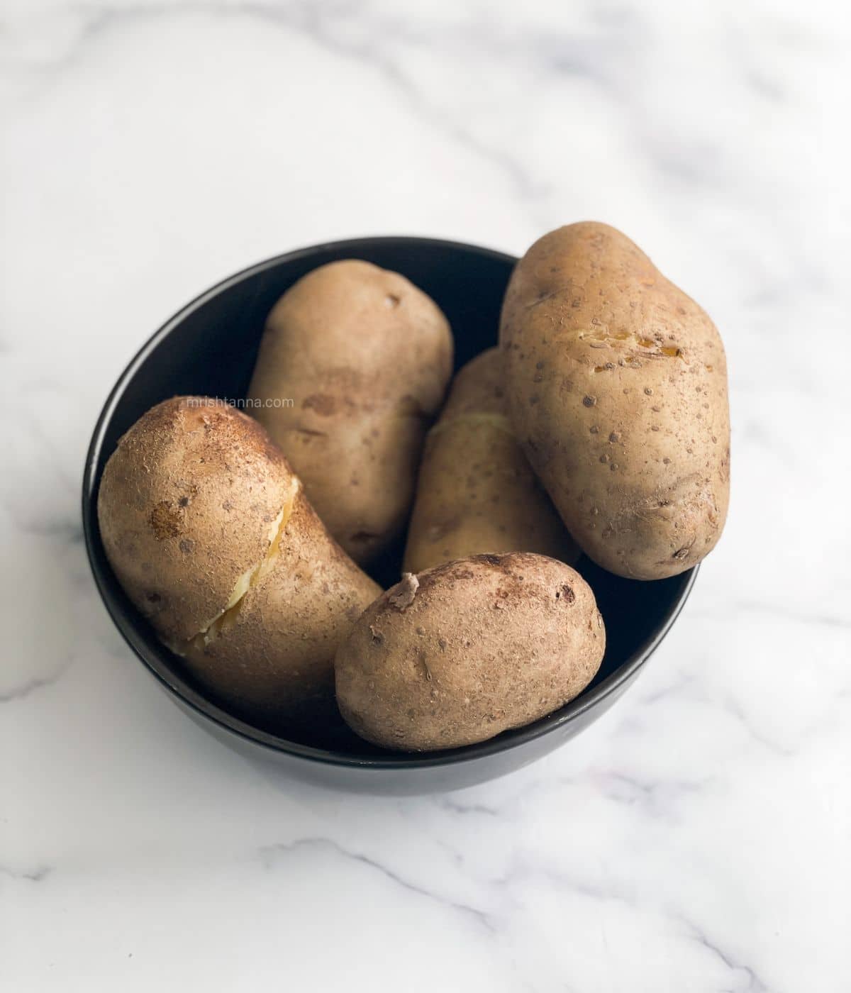 A bowl is with boiled russet potatoes.