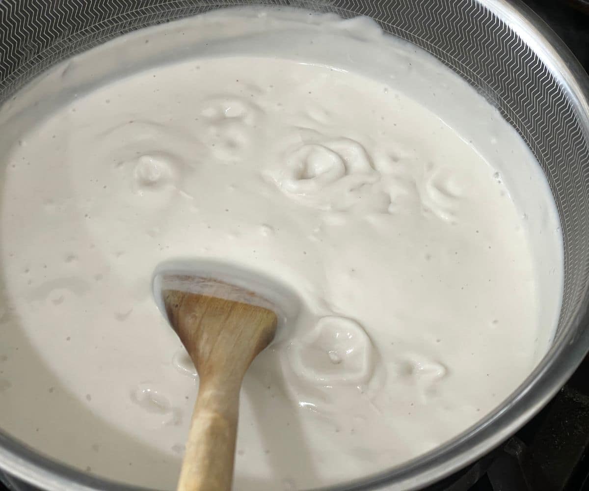 A pot of cashew milk is on the stove top.