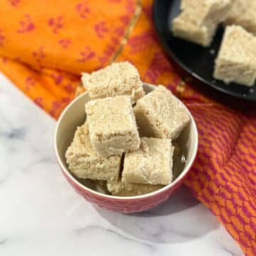 A bowl of Nariyal barfi is on the surface.