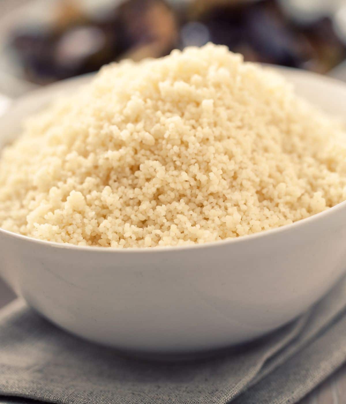 A bowl of cooked couscous is on the cloth napkin.