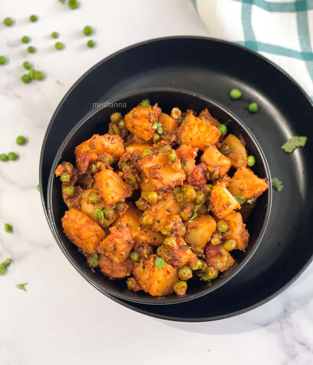 A bowl of aloo matar dry curry is on the plate.