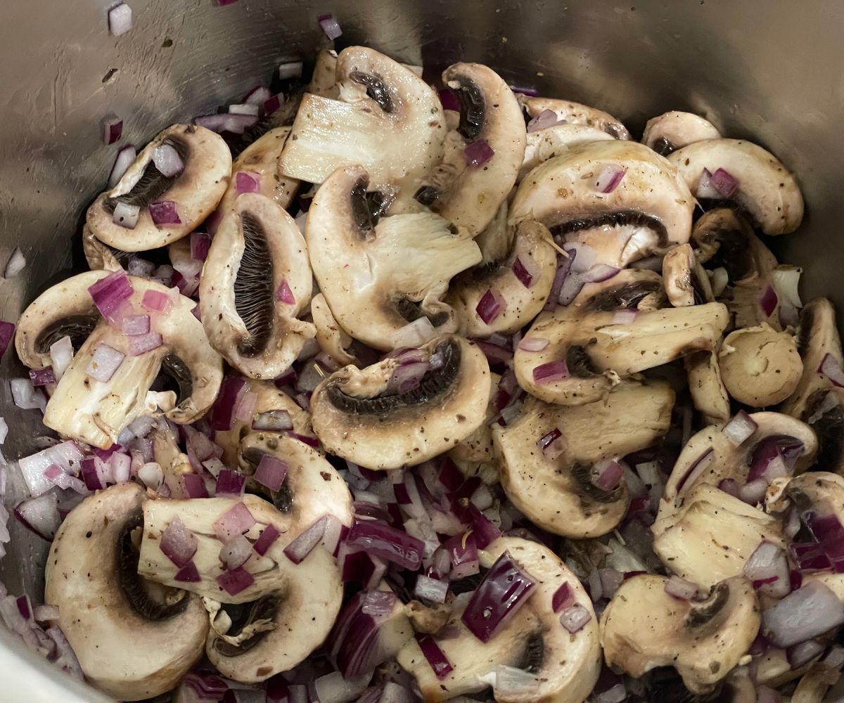 A pot has mushrooms and seasoning for barley risotto.