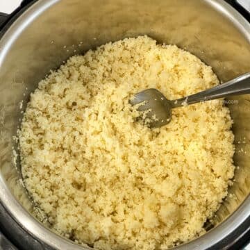 An instant pot has cooked couscous and a fork is inside.