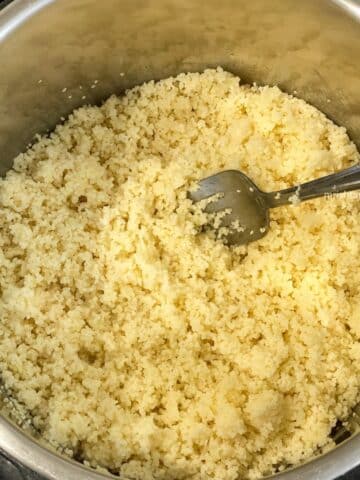 An instant pot has cooked couscous and a fork is inside.