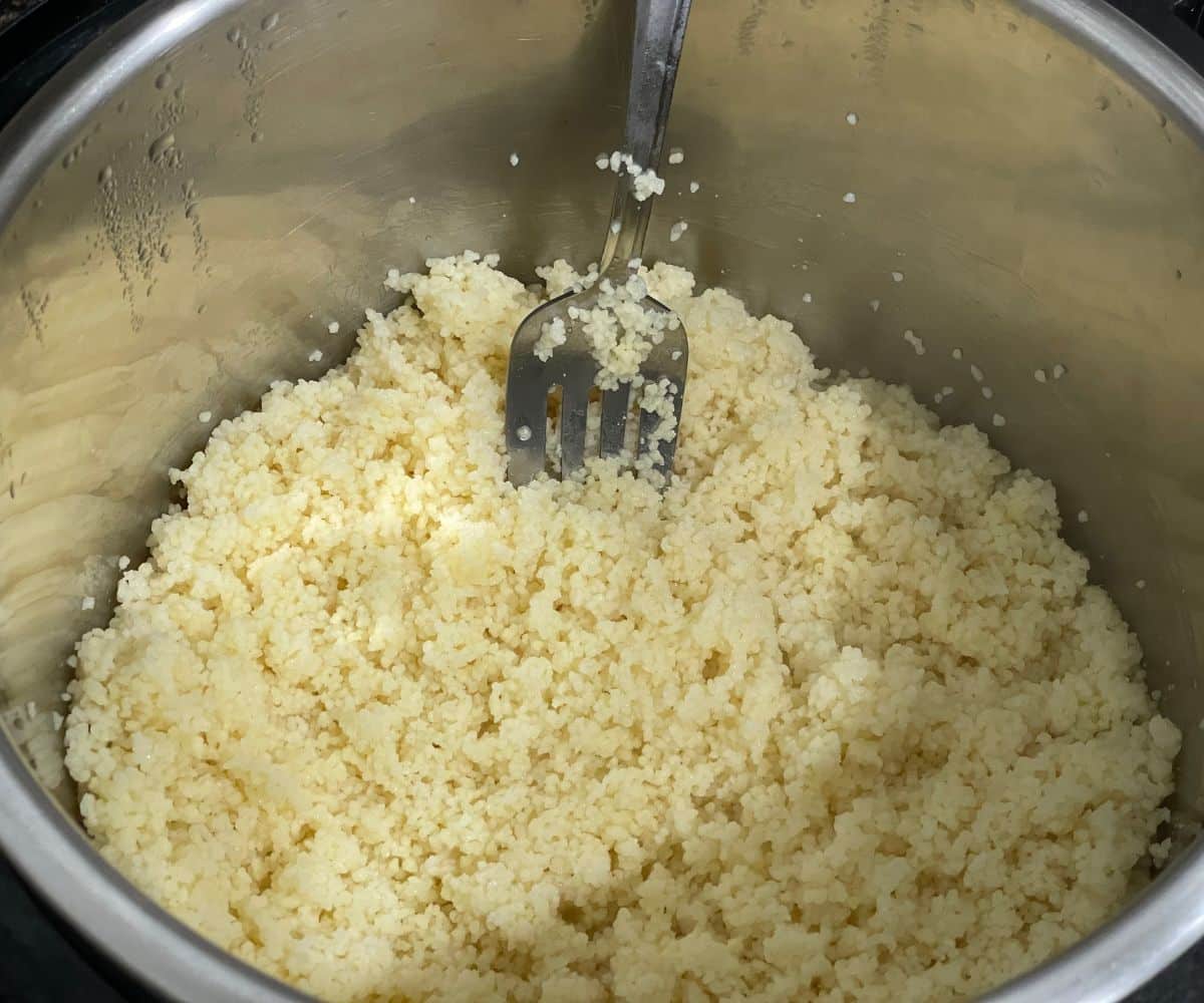 An instant pot has cooked couscous.