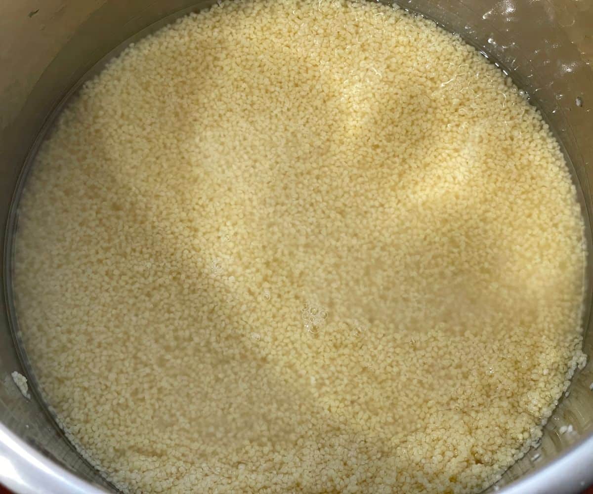An instant pot has couscous and water.