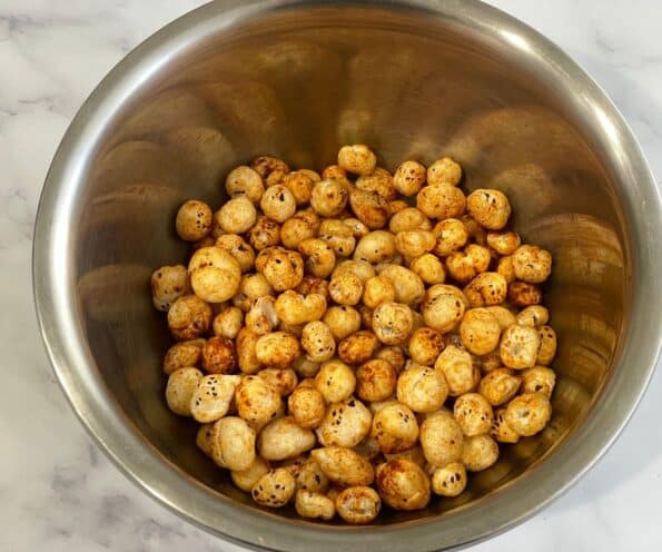 A bowl is with spice coated roasted makhana.