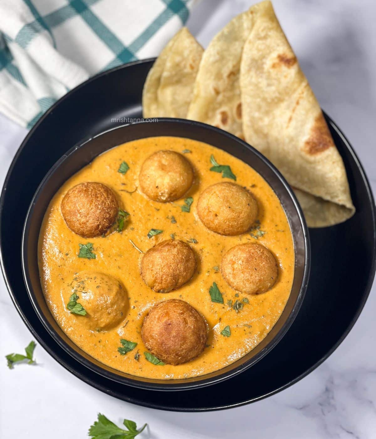 A bowl is full of vegan malai kofta curry.