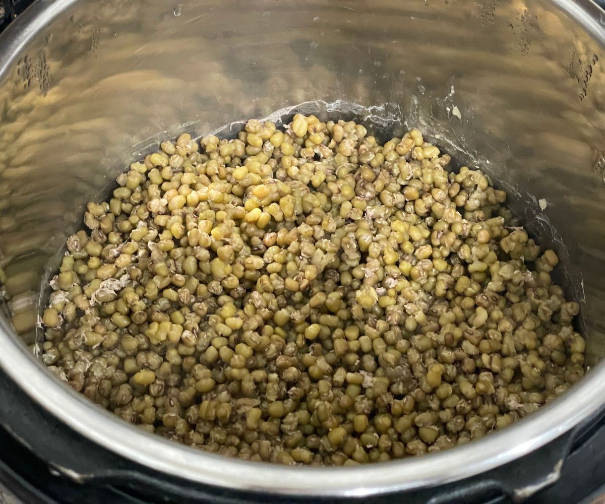 An instant pot is with cooked mung beans.