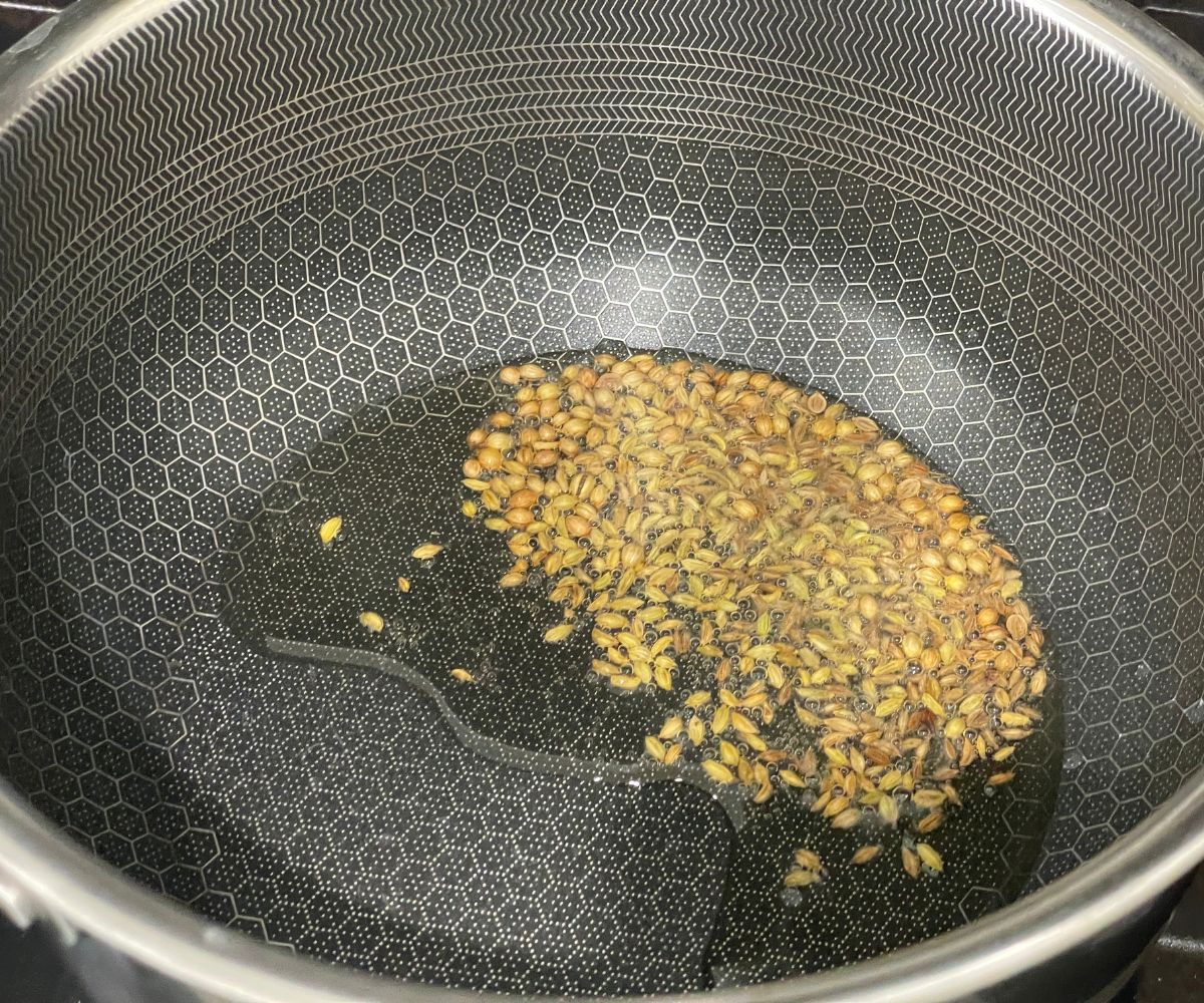 A pan is with wholes spices and oil over the heat.