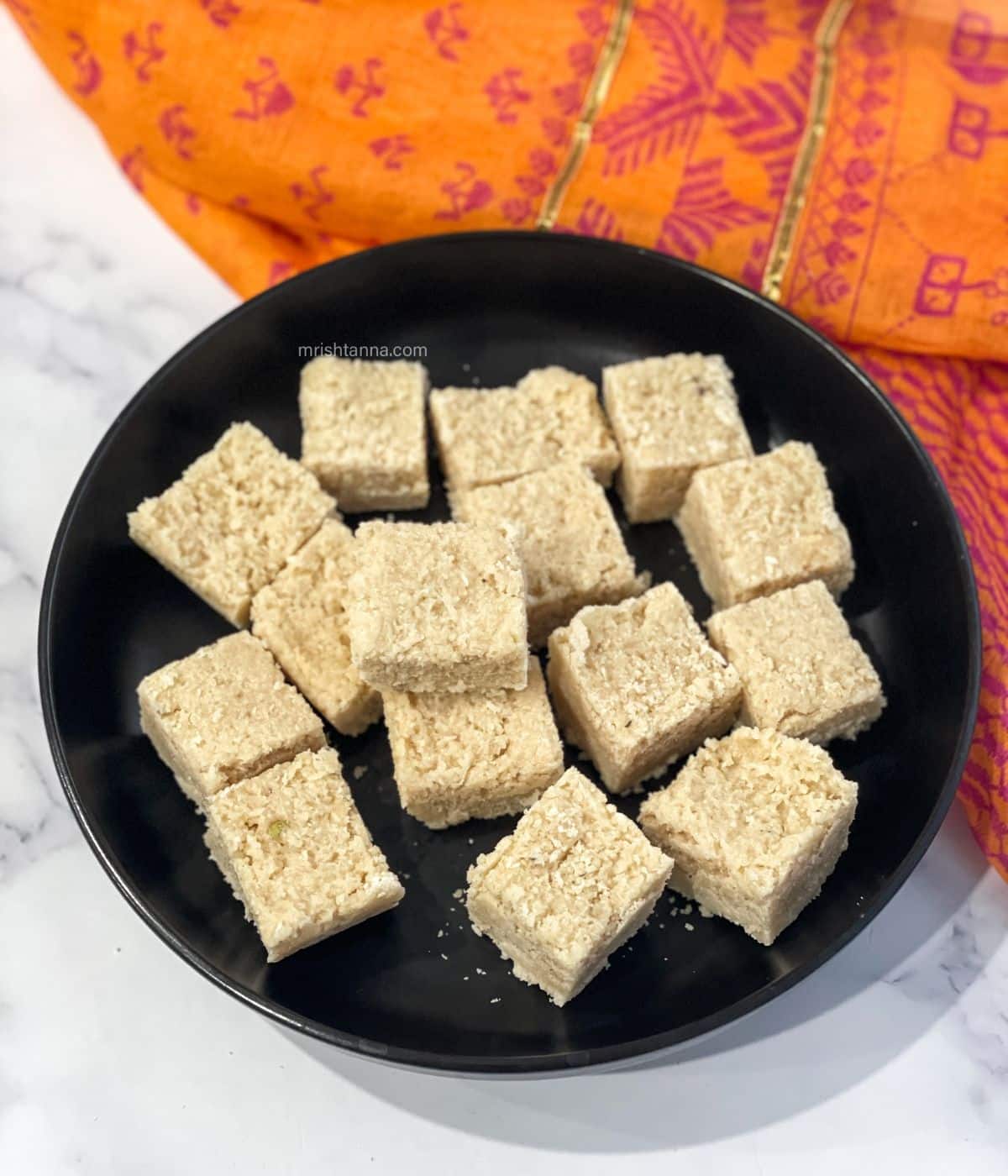 A plate is full of vegan coconut burfis.