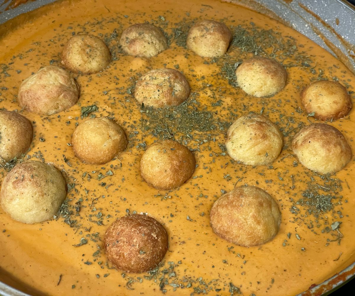 A pan has malai curry and topped with air fried koftas.