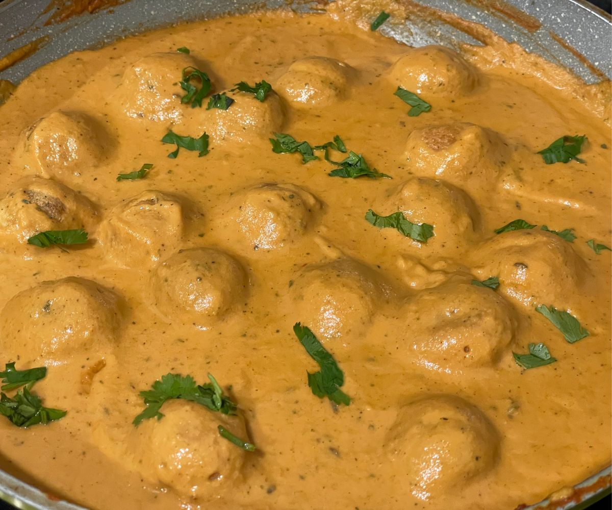 A pan is filled with vegan malai kofta curry.