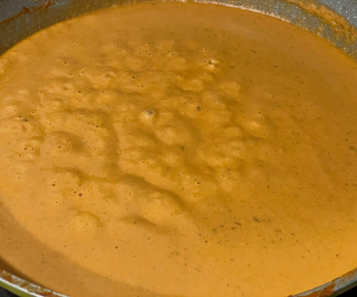 A pan has blended malai kofta curry sauce on the heat.