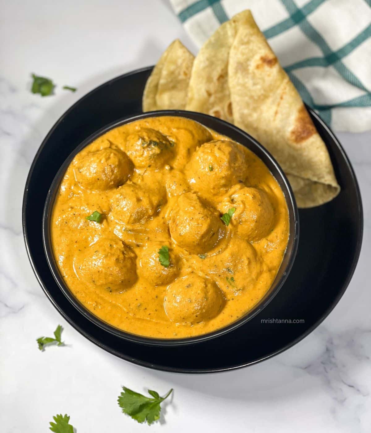 Vegan malai kofta curry is in the bowl along with chapati.