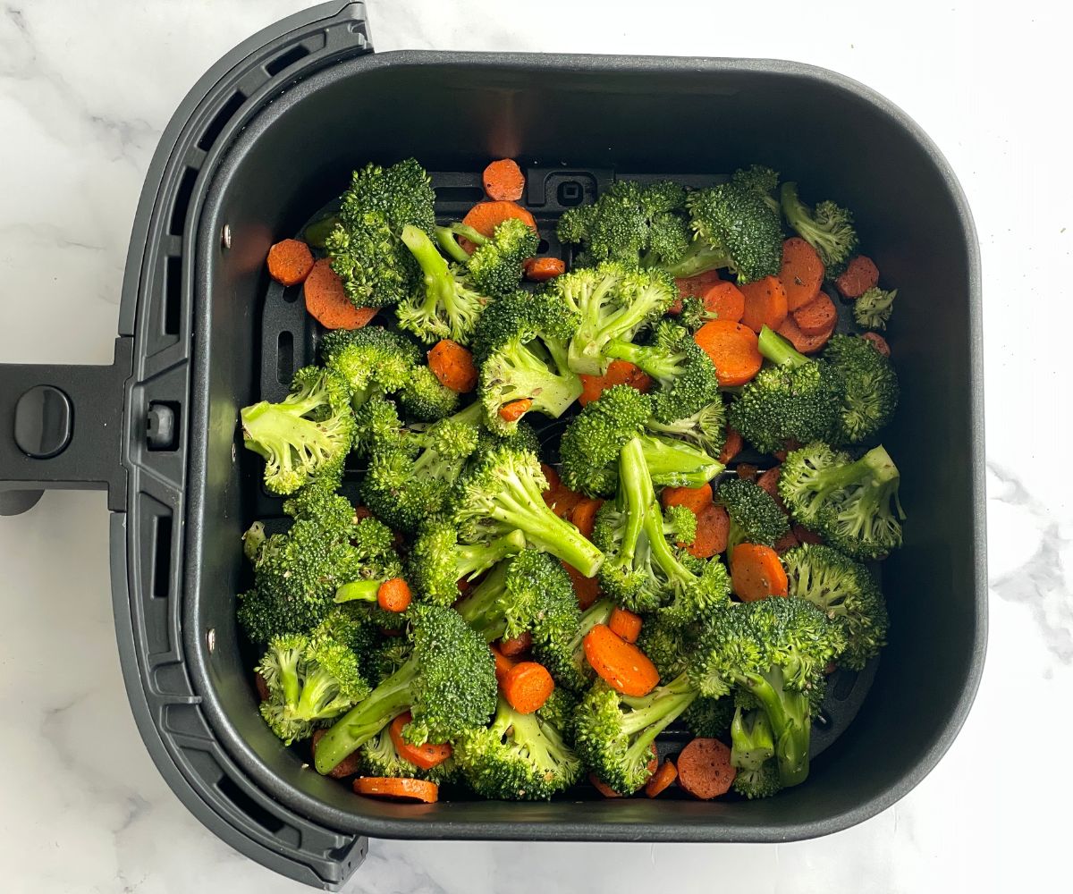 Air fryer basket filled with broccoli and carrots.