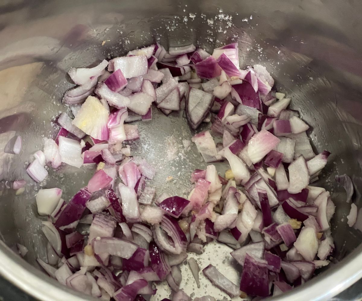 An instant pot has sauteed chopped onions, garlic and ginger.