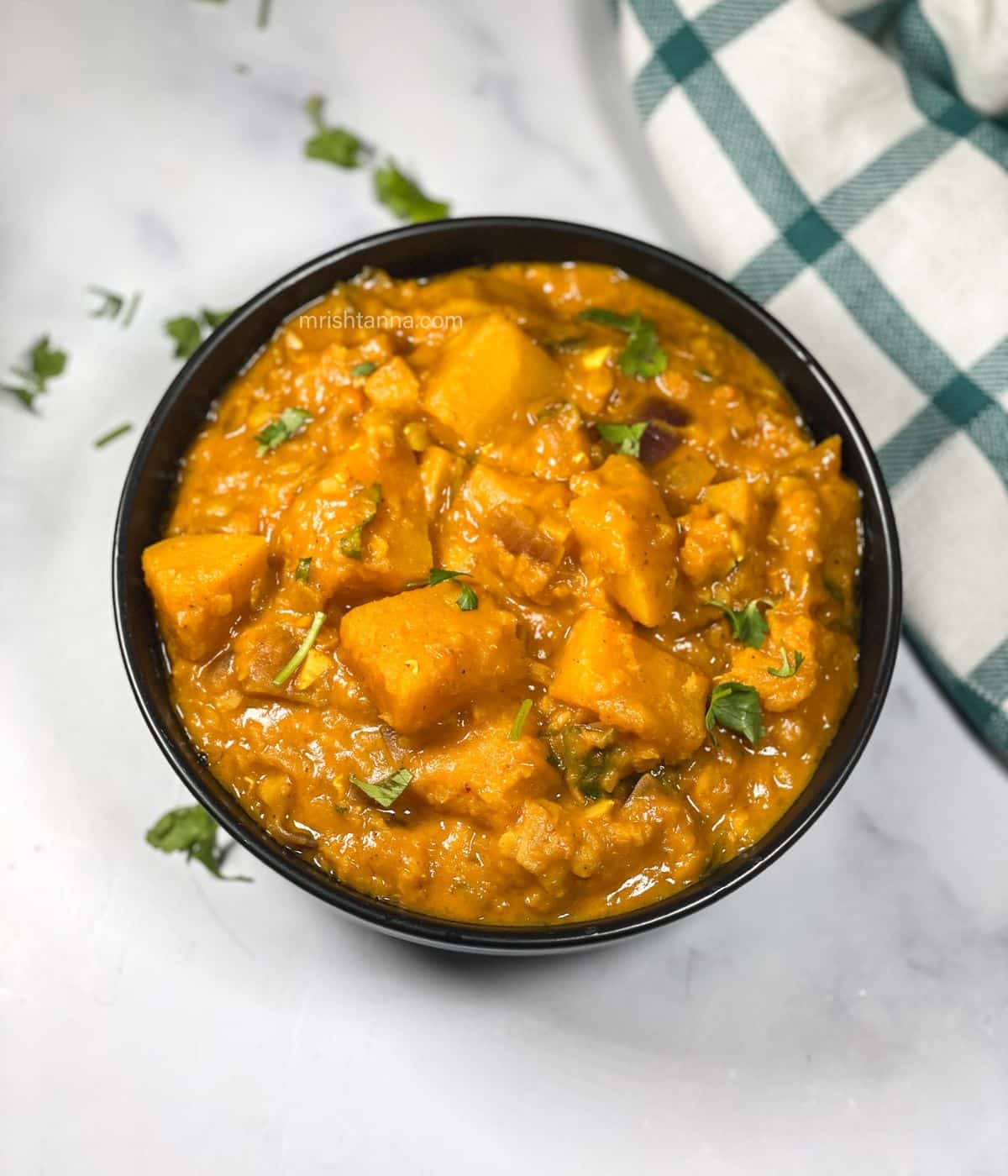A bowl has full of butternut squash lentil curry.