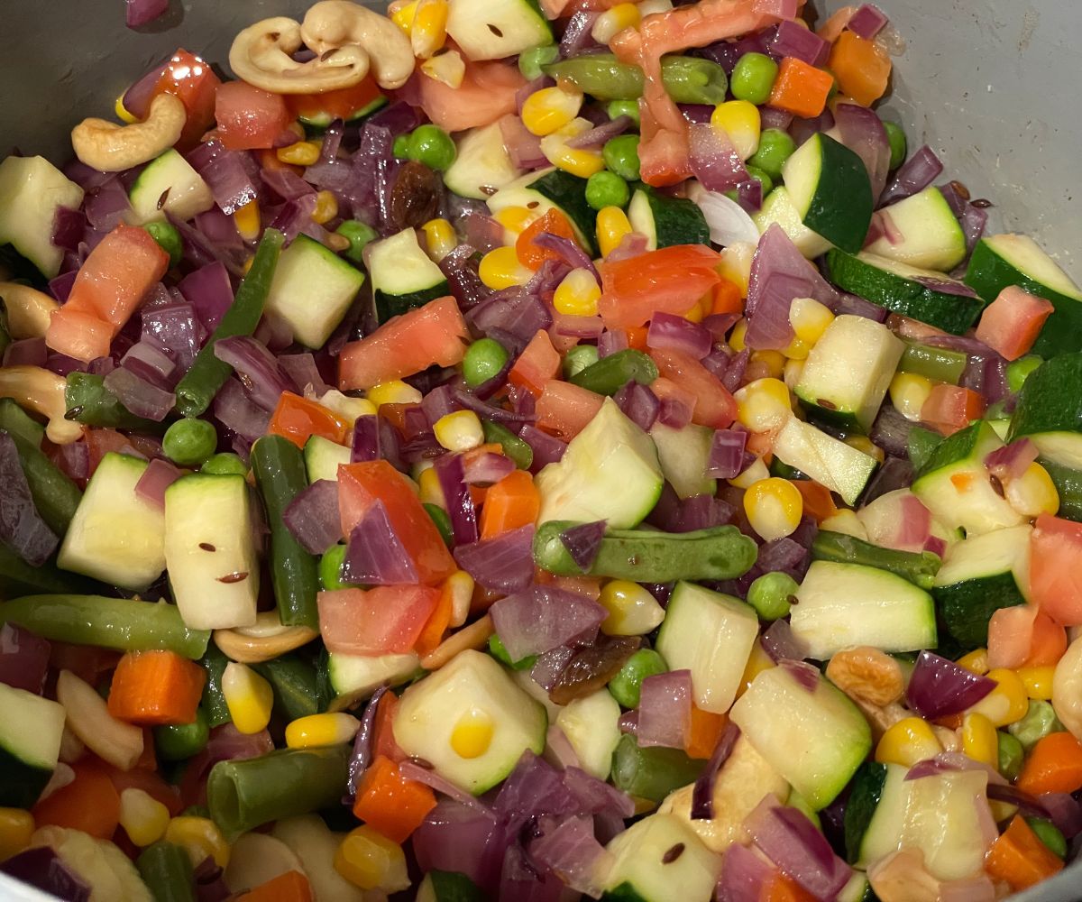 A heated pot has mixed vegetables and spices.
