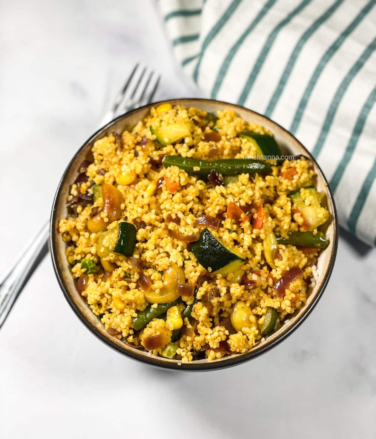 A bowl of curried couscous  is on the table.