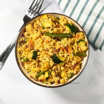 A bowl has curried couscous salad.