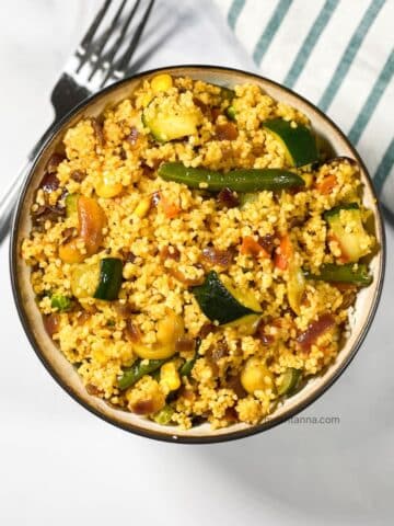 A bowl has curried couscous salad.