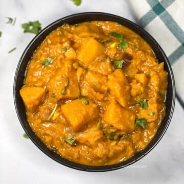 A bowl of butternut squash curry is on the table.