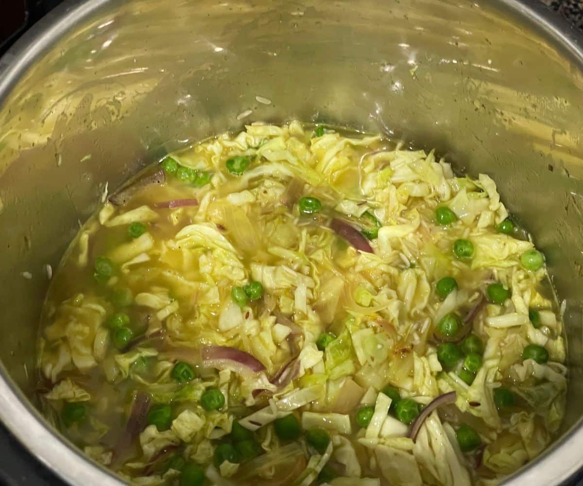 An instant pot is with cabbage rice ingredients.