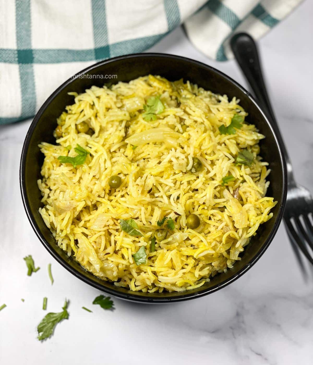 A bowl of cabbage rice is on the table with a fork by the side.