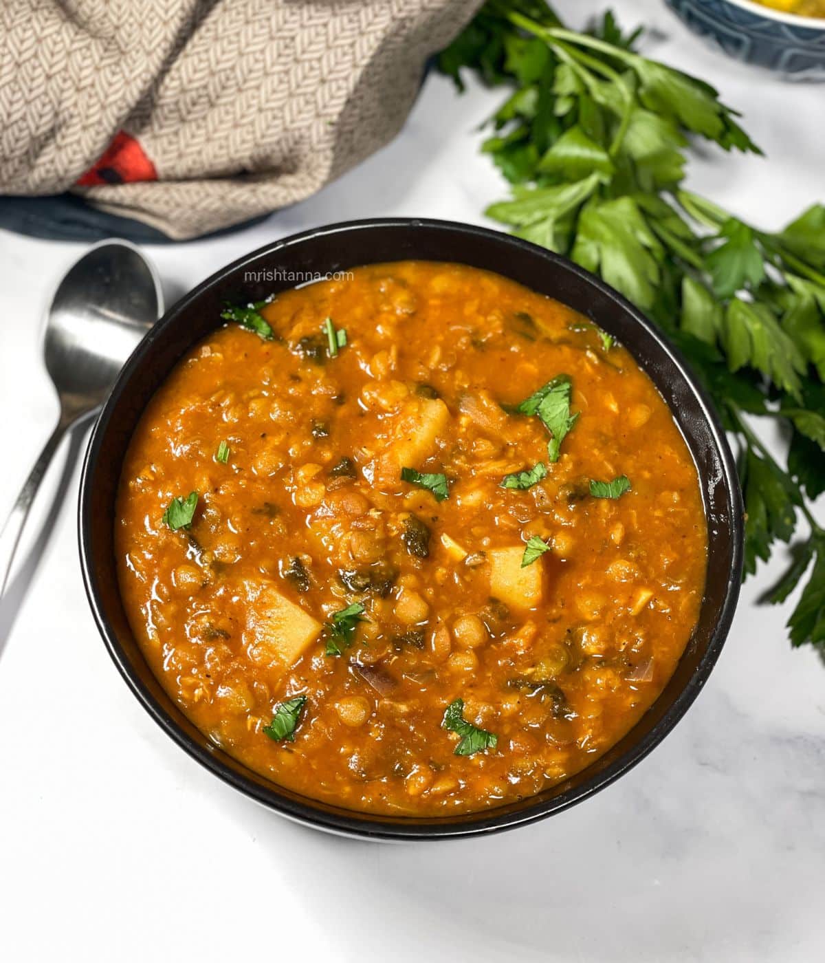 A bowl of vegan lentil soup is on the surface.