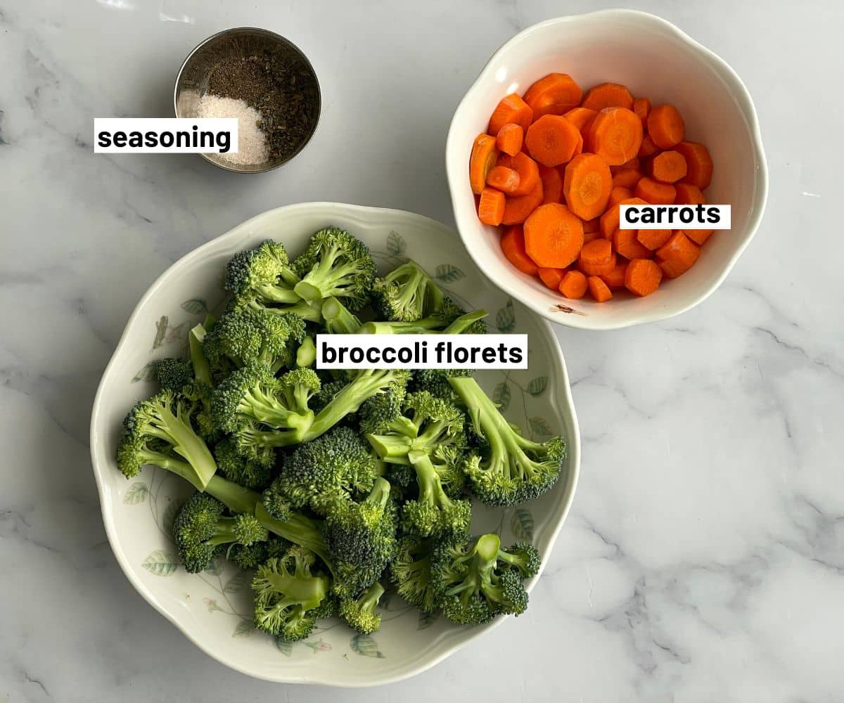 A table is with carrots, broccoli and seasonings on the bowls.
