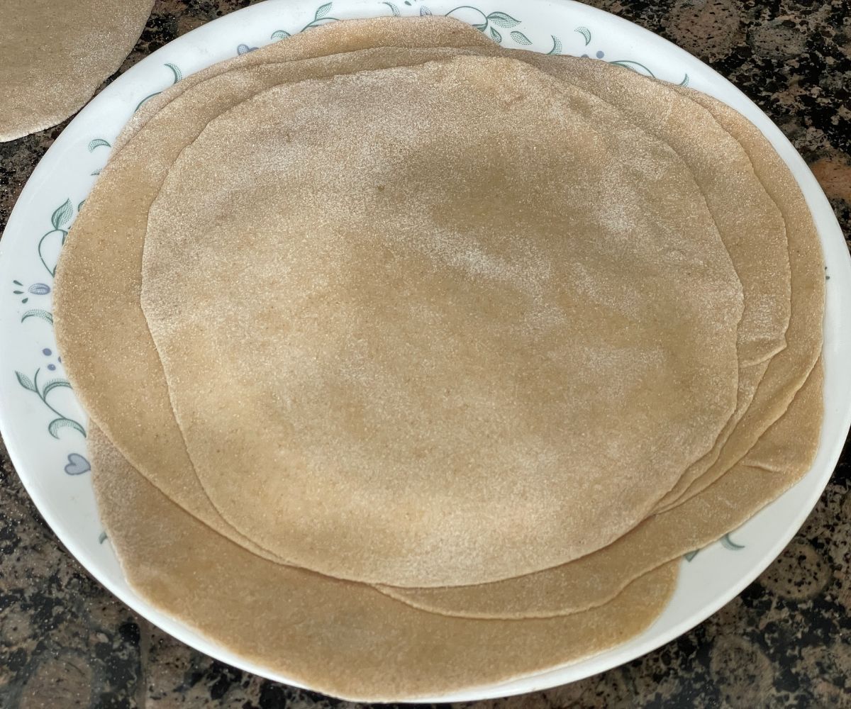 A plate has a stack of rolled chapati dough.