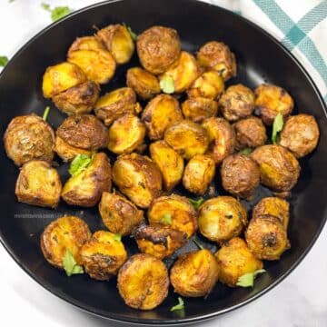 A plate has air fryer Tandoori Potatoes.