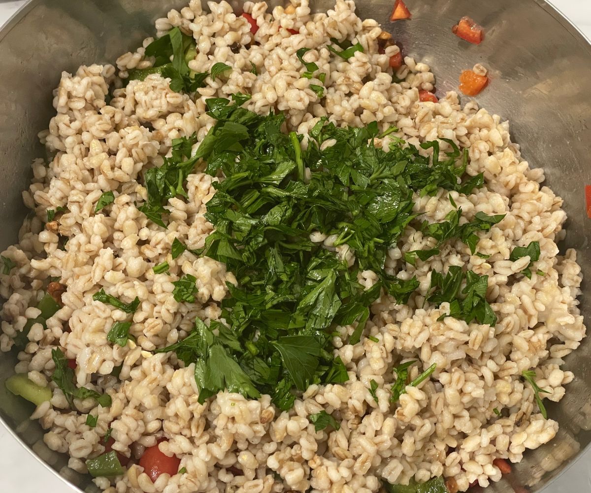 A bowl has barley salad ingredients.