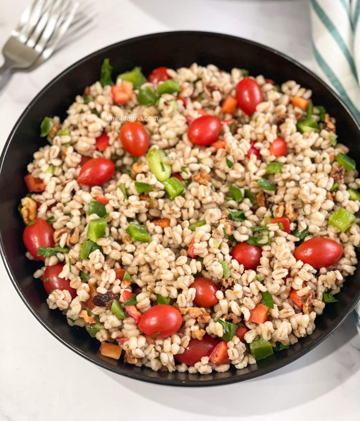 A plate is full of vegan barley salad.