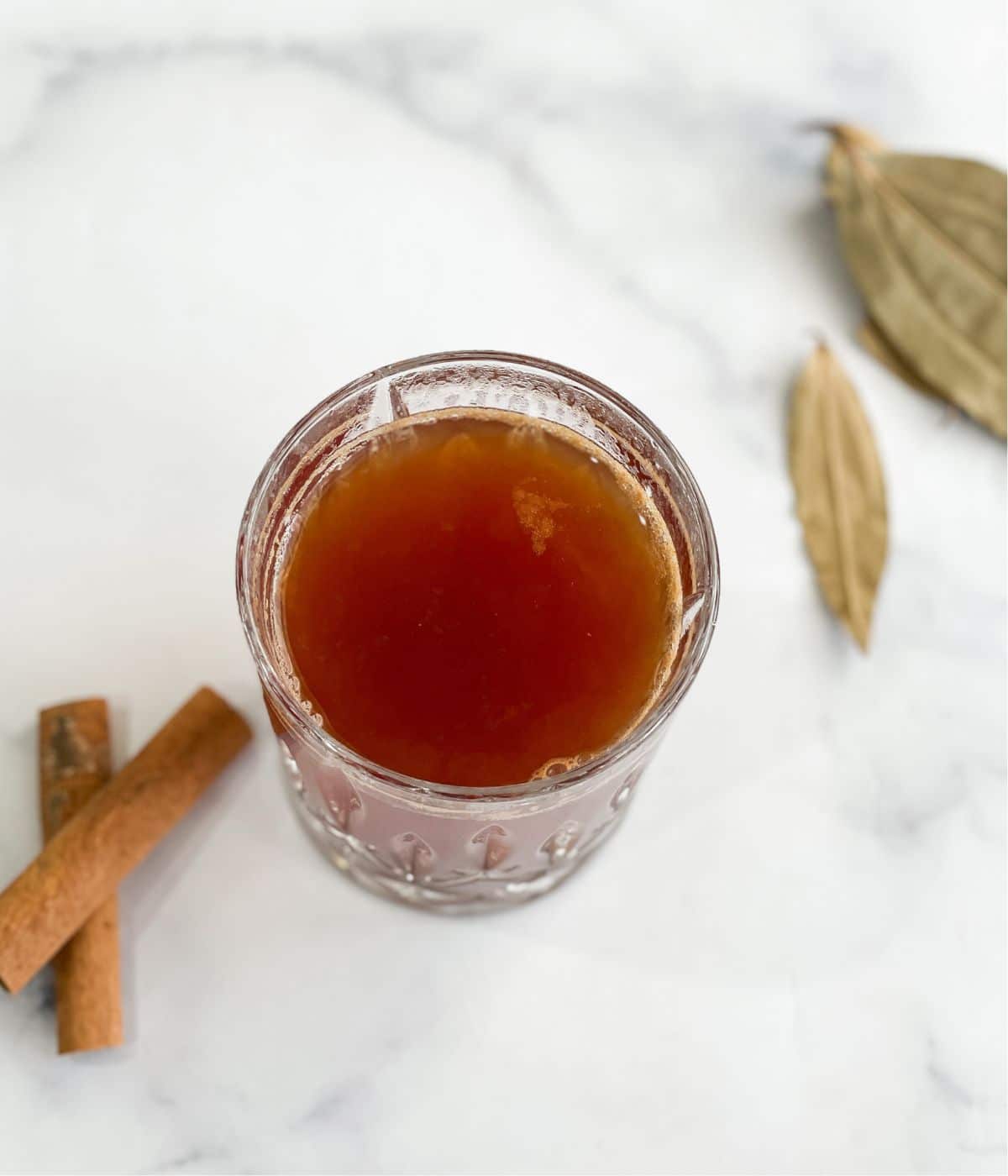 A glass is with a bay leaf cinnamon tea recipe.