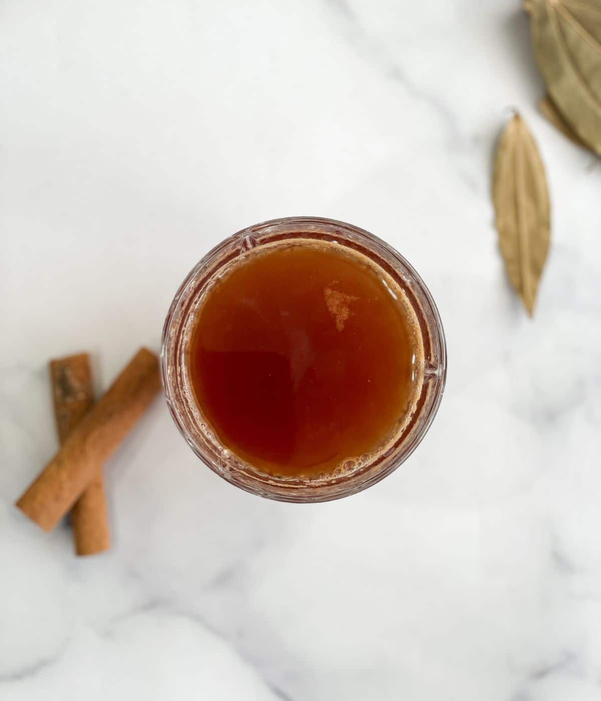 A glass of cinnamon and bay leaf tea is on the surface.