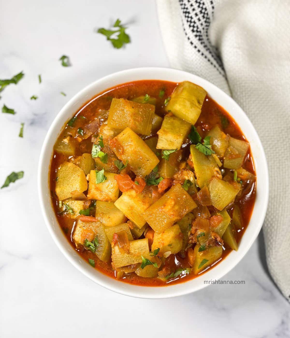 A bowl is full of Lauki sabzi topped with cilantro.