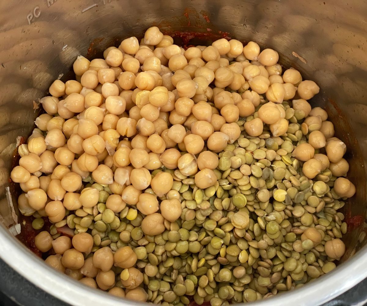 An instant pot has chickpeas and lentils along with spices.