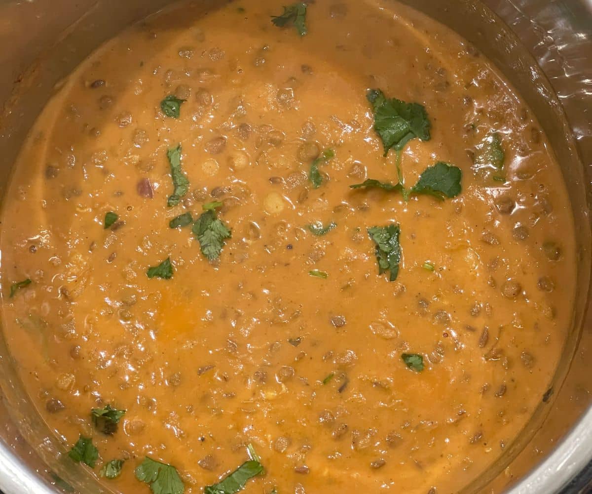 A pot has chickpea and lentil curry with coconut milk.