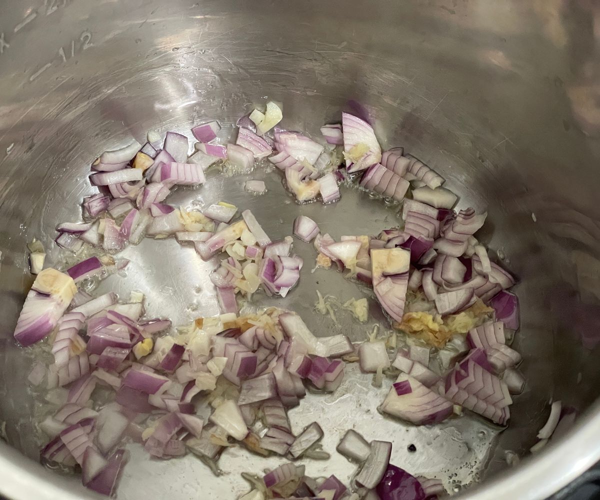 An instant pot has garlic and onions.
