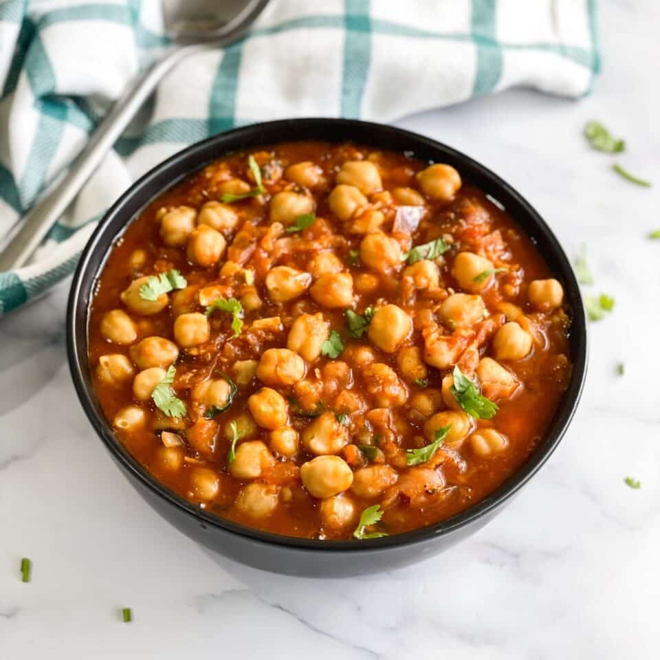 A bowl of chana masala is on the table.