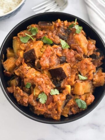 A bowl is full of Indian Eggplant masala curry.