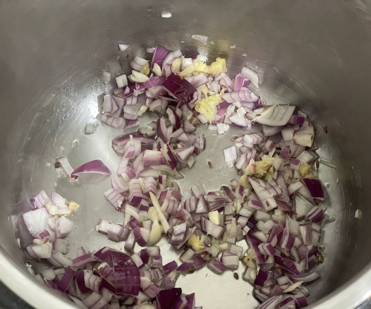 Instant Pot has chopped onions and spices.