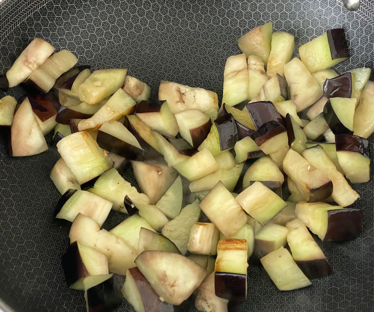 A pan has sauteed eggplants on the stove top.