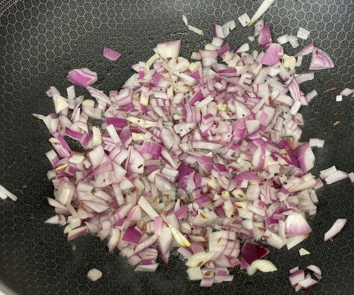 A pan has chopped onions over the heat.